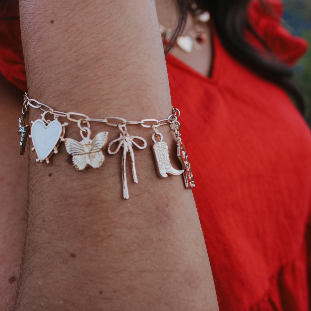 Bracelet with various charms on a person's wrist, wearing a red garment.